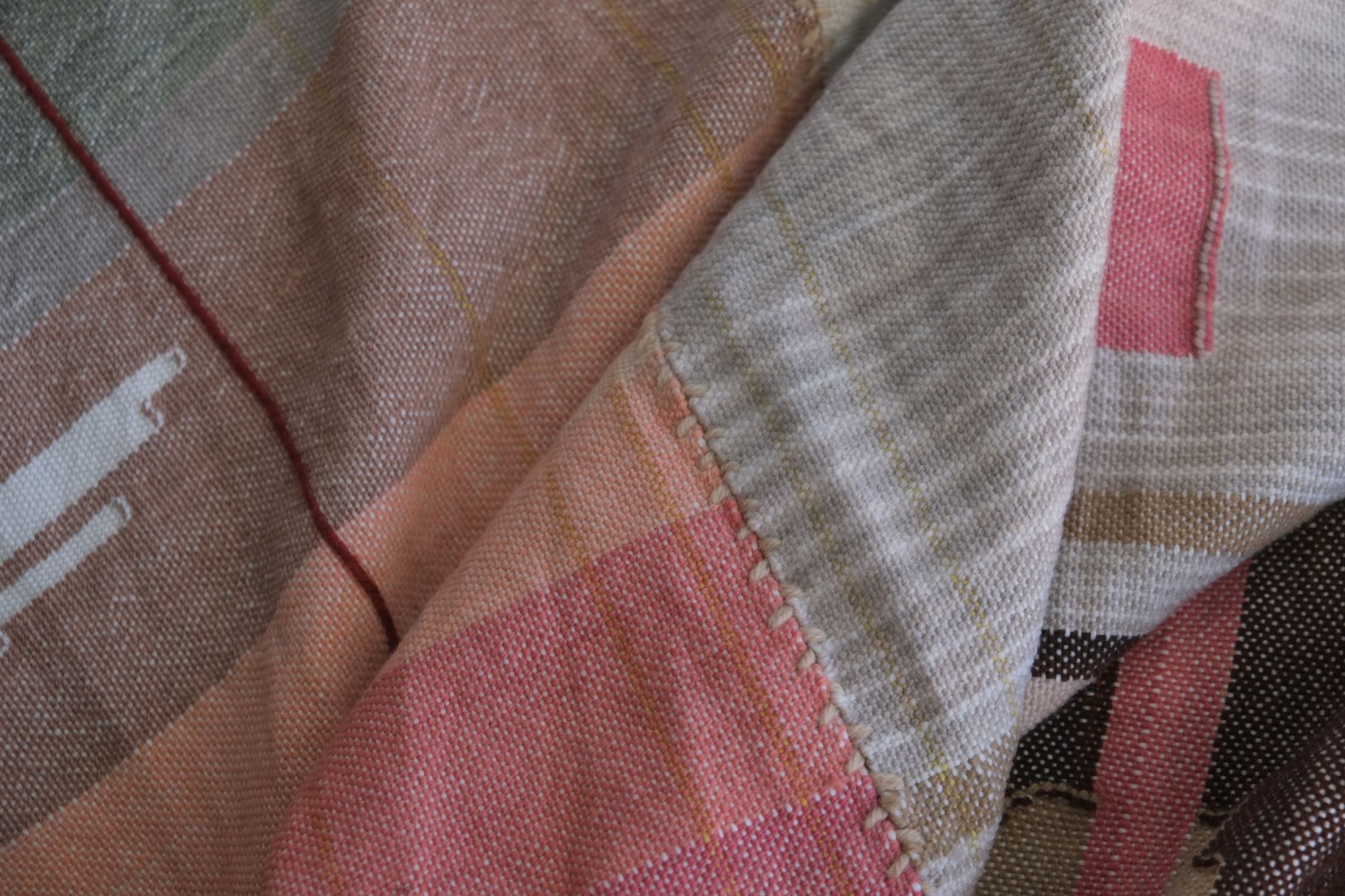 Detail of Handwoven Naturally Dyed Merino Ancient Dialogue Blanket laying on a wooden floor