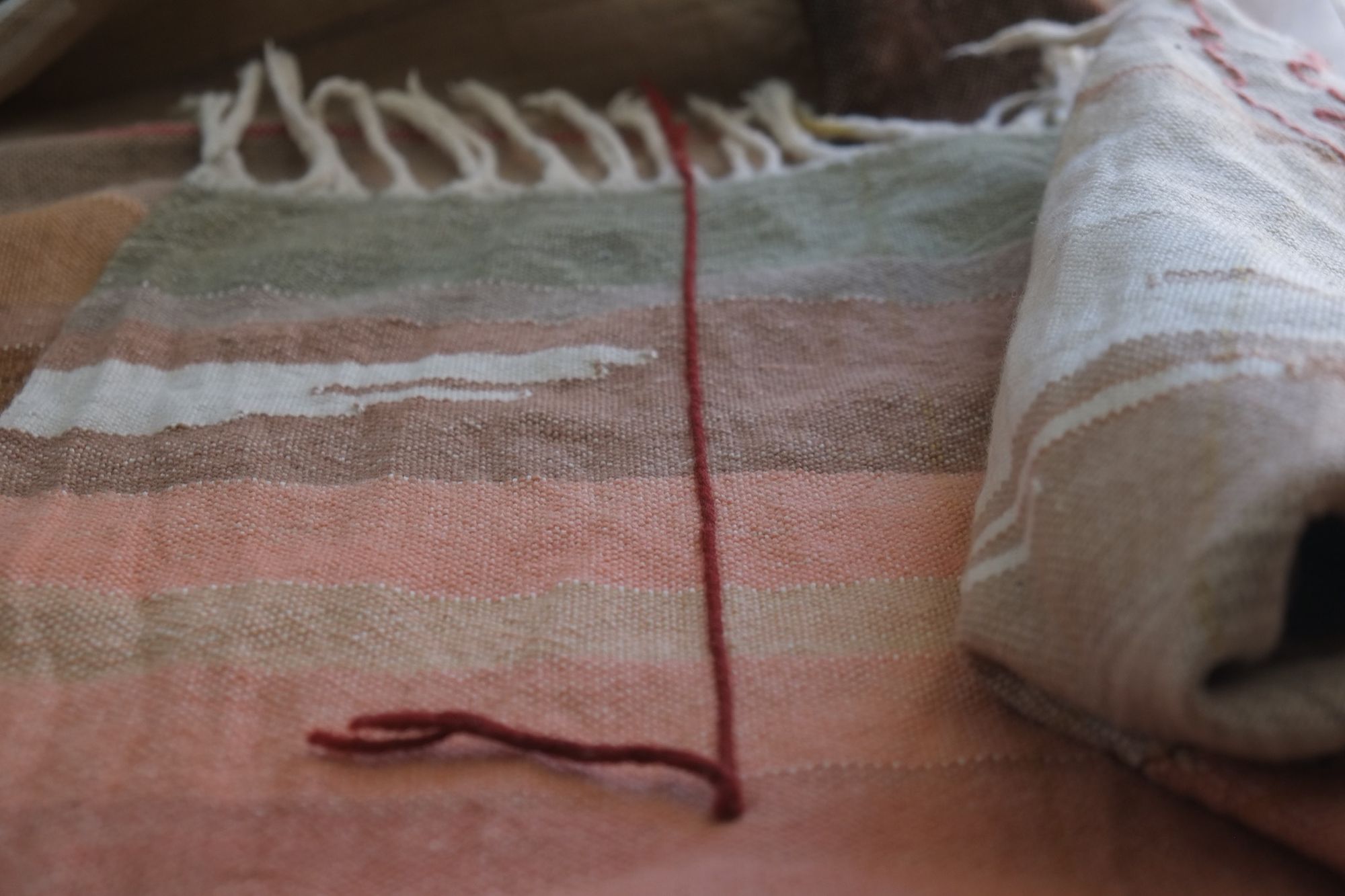 Detail of Handwoven Naturally Dyed Merino Ancient Dialogue Blanket laying on a wooden floor