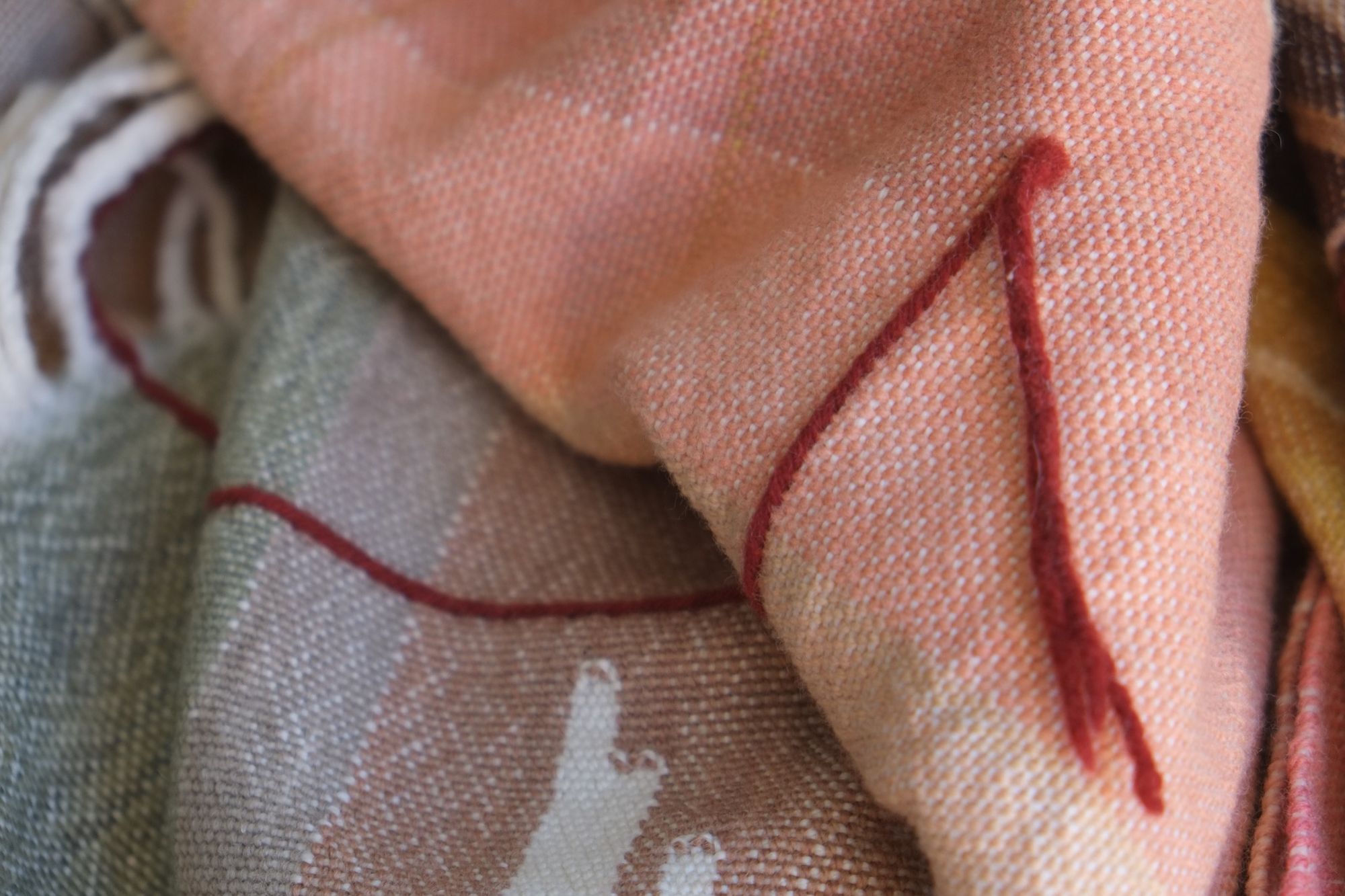 Detail of Handwoven Naturally Dyed Merino Ancient Dialogue Blanket laying on a wooden floor