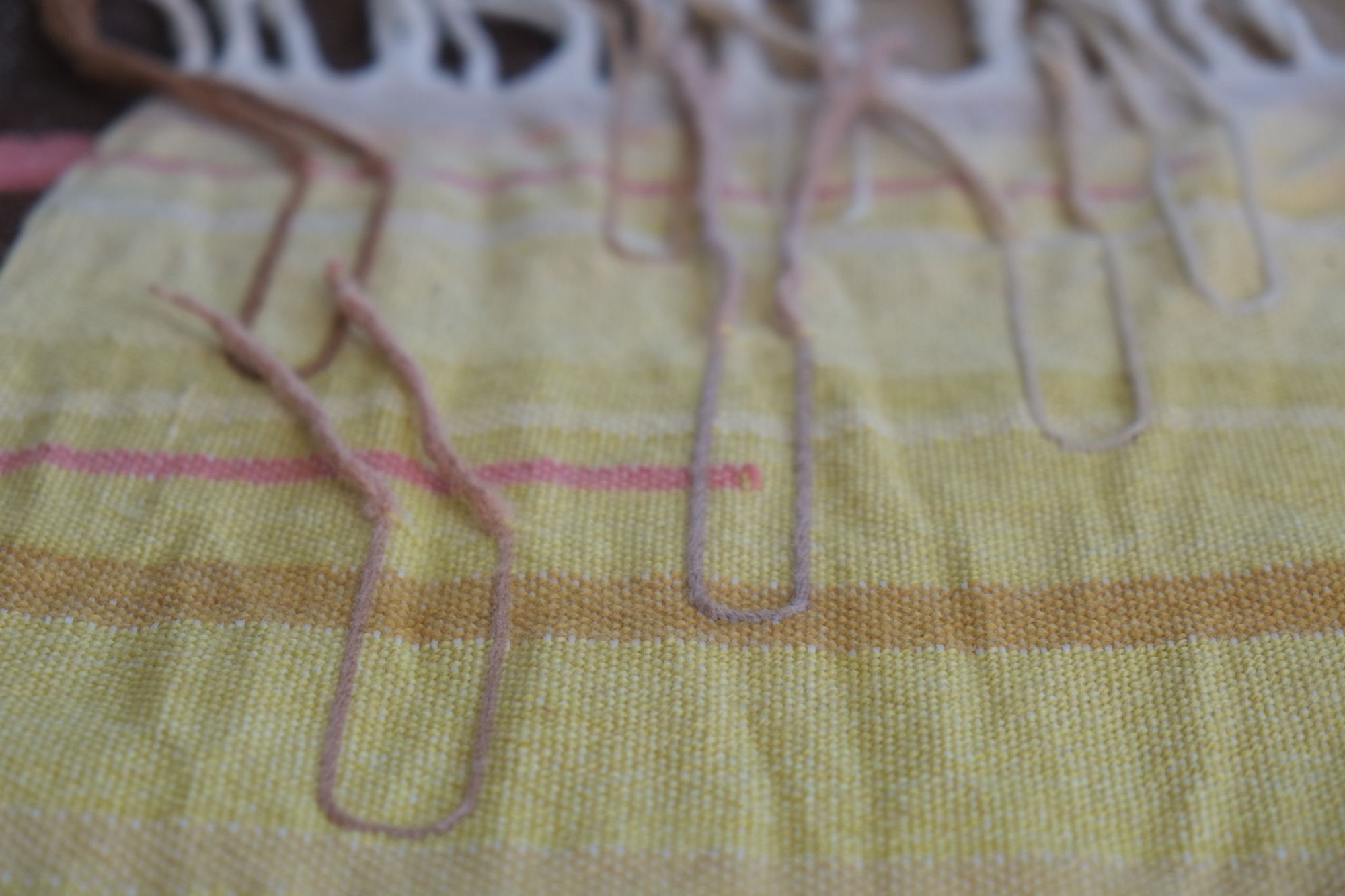 Detail of Handwoven Naturally Dyed Merino Ancient Dialogue Blanket laying on a wooden floor