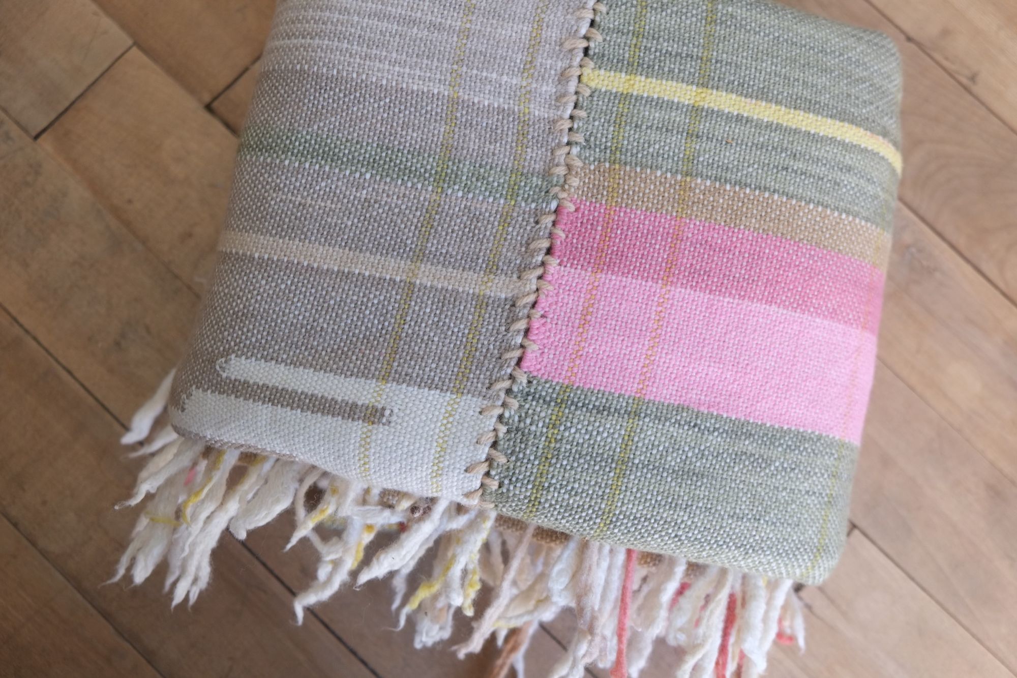 Handwoven Naturally Dyed Merino Ancient Dialogue Blanket laying on a wooden floor