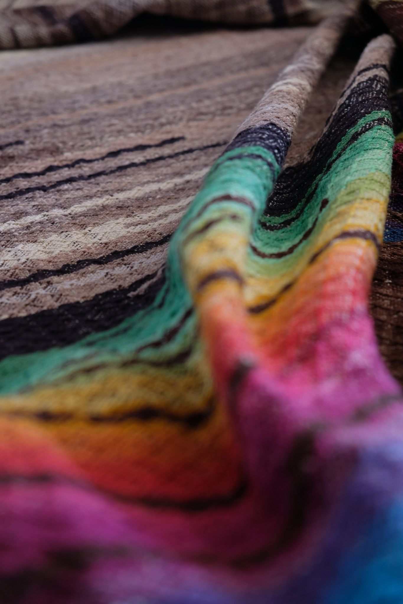 detail of Multi colored handwoven raw silk fabric laying on a wooden floor