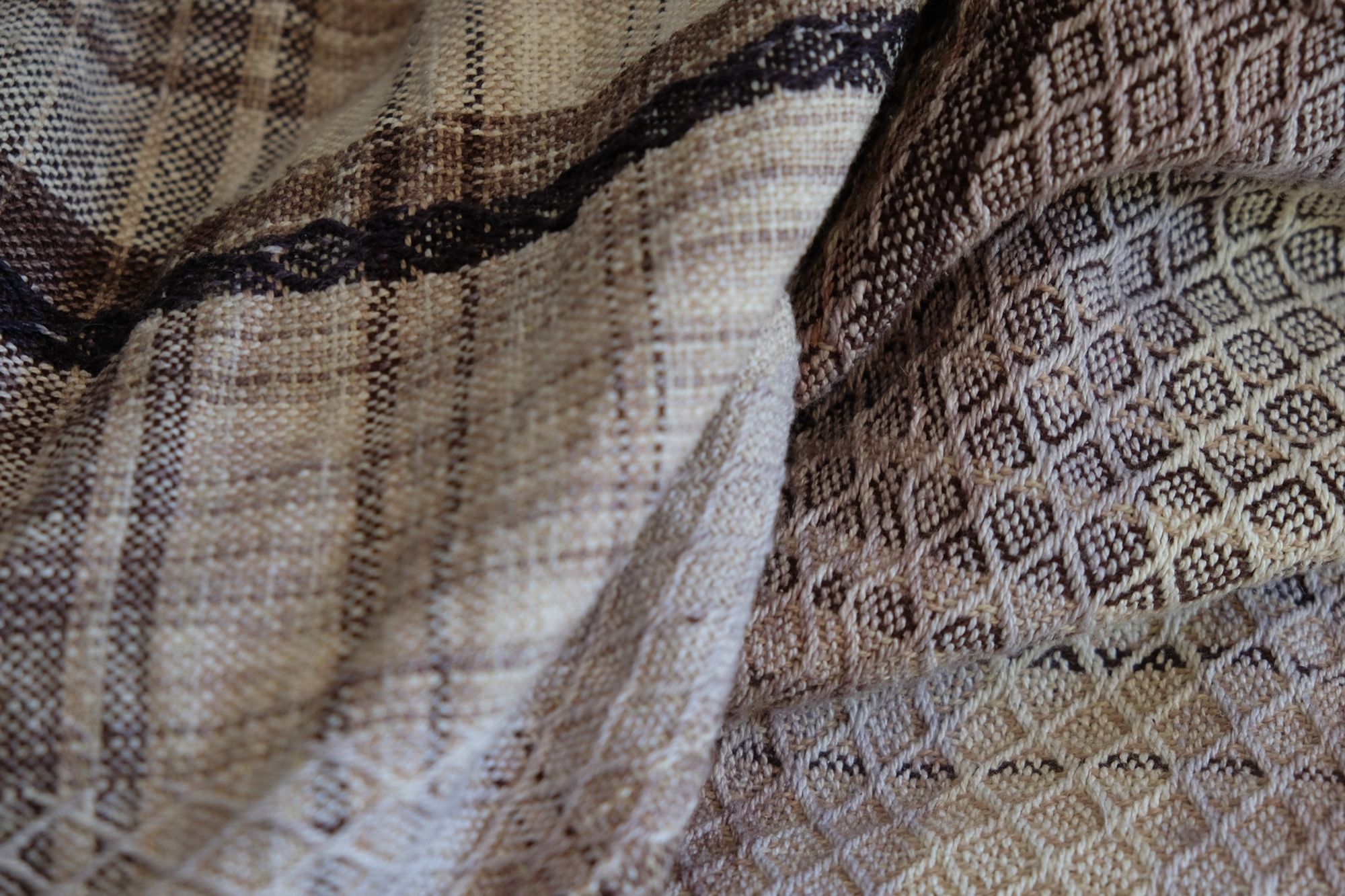 detail of Multi colored handwoven raw silk fabric laying on a wooden floor