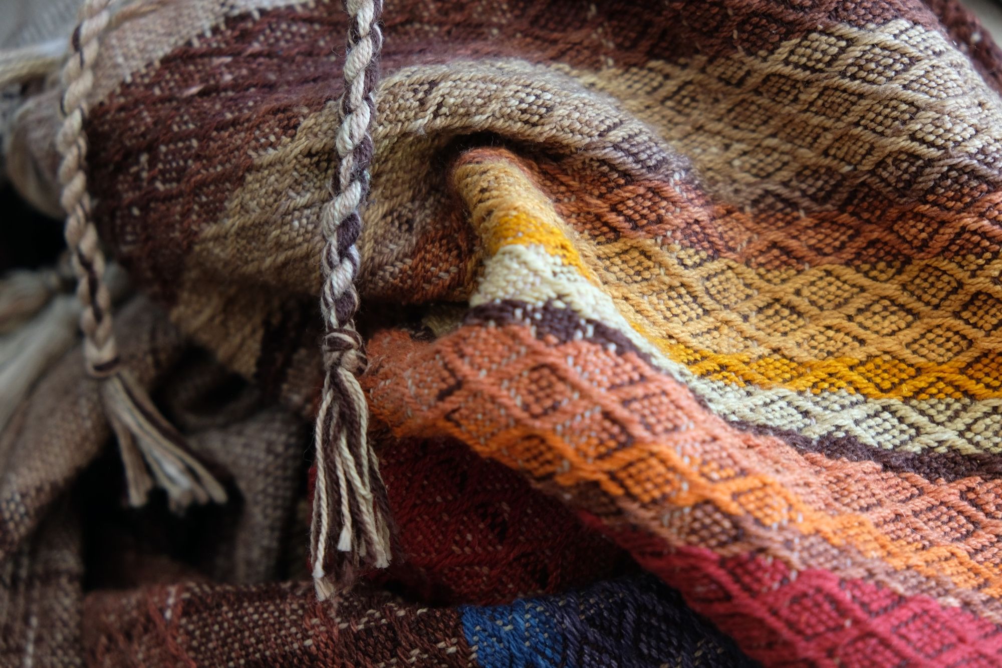 Multi colored handwoven raw silk fabric laying on a wooden floor
