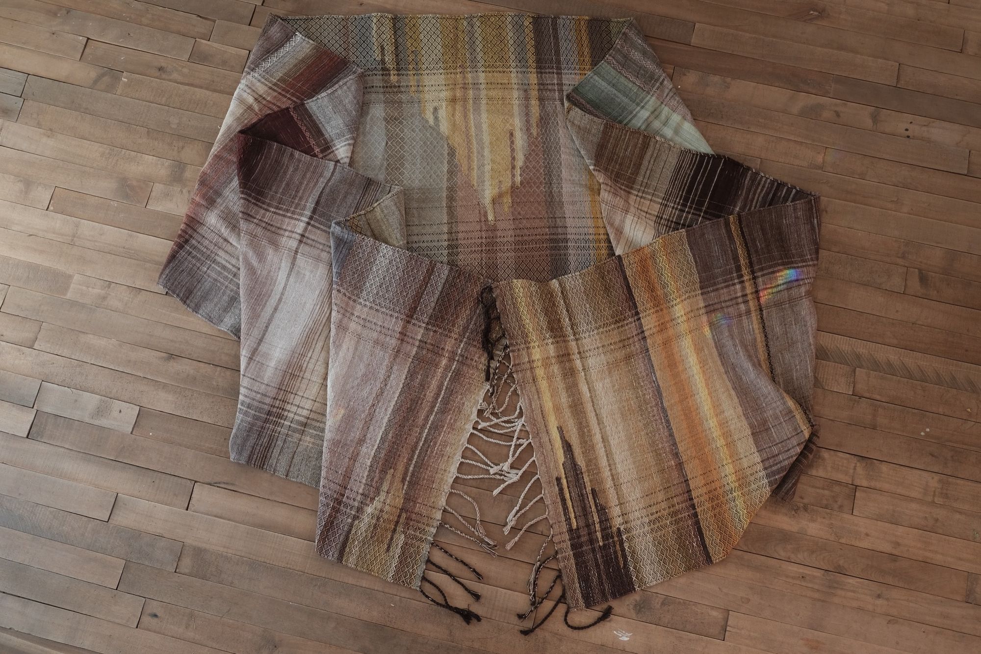 soft yellow, green, orange and brown Handwoven fabric laying on a wood floor