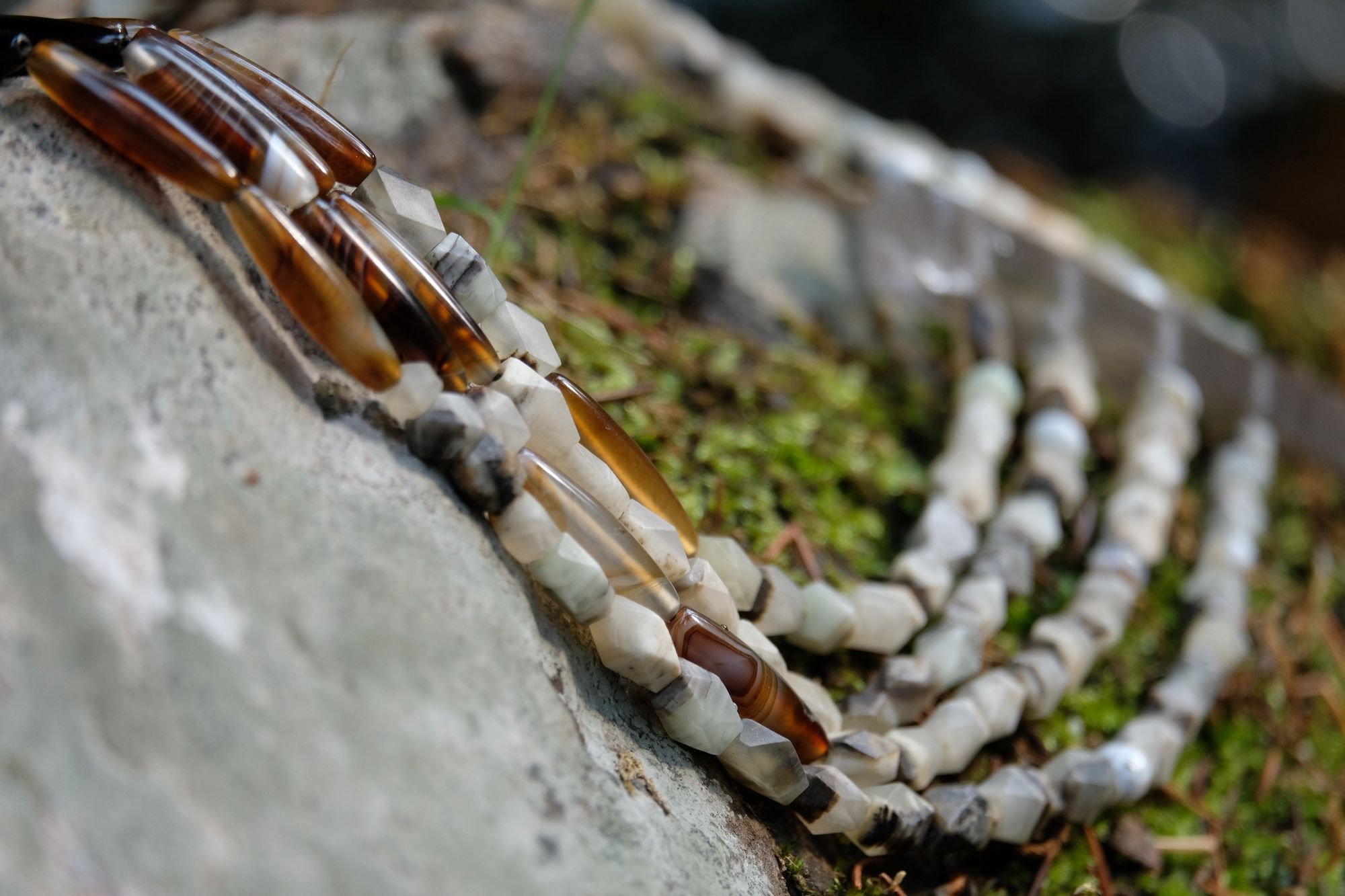 Detail of four strand tan, green and brown faceted jade and quartz point necklace