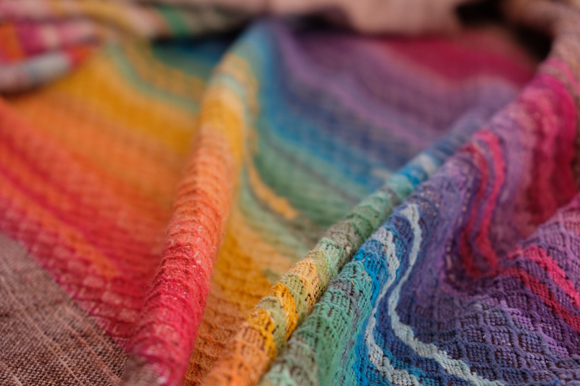 detail of handwoven fabric with textured diamond weave in rainbow colors with browns and tans