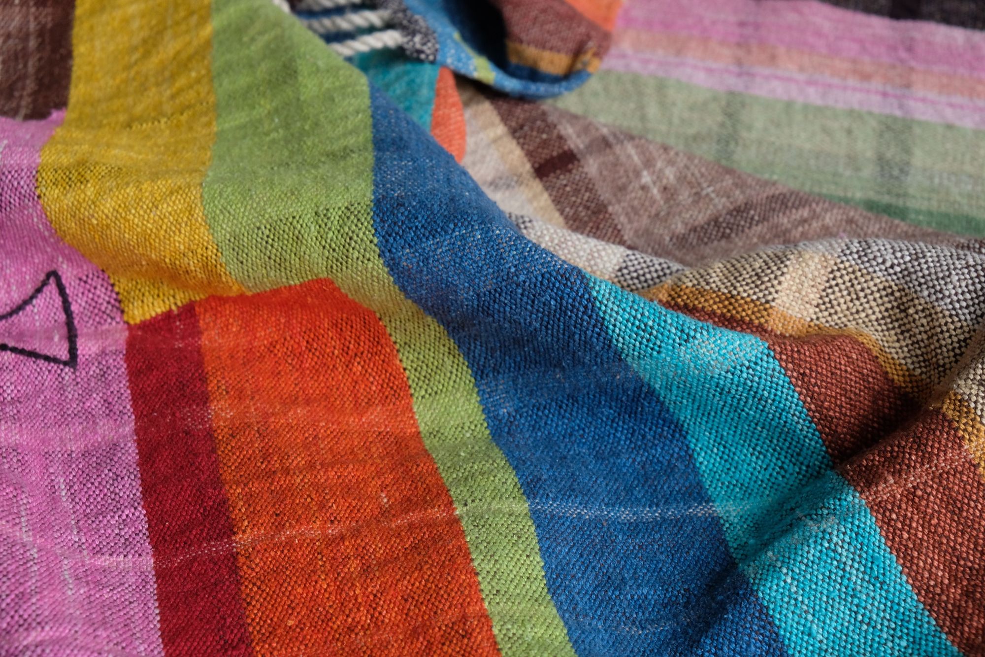 many colored handwoven fabric laying on a wooden floor