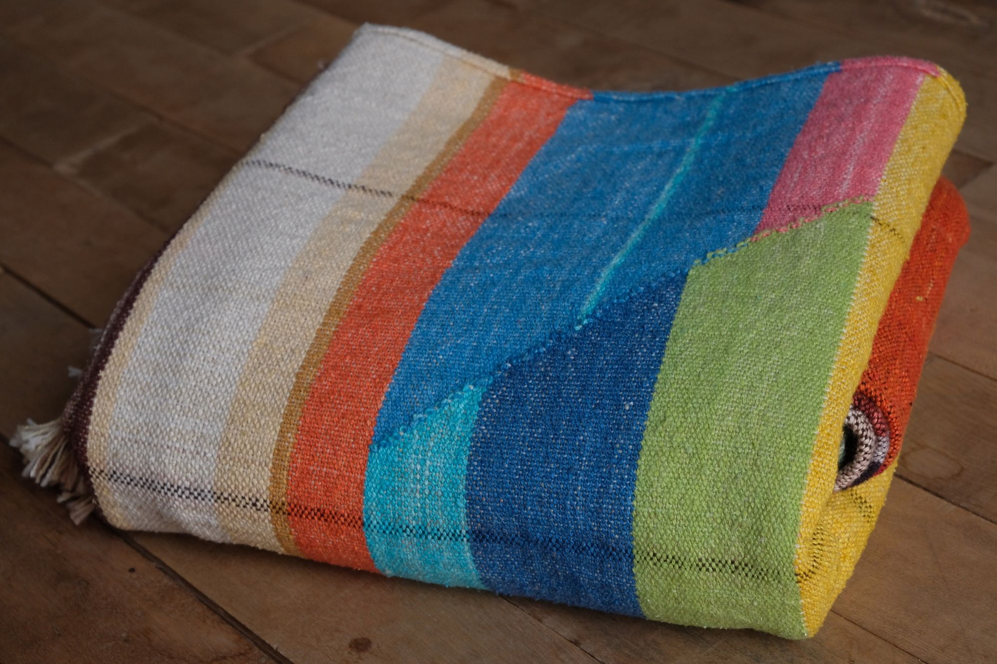 many colored handwoven fabric folded laying on a wooden floor