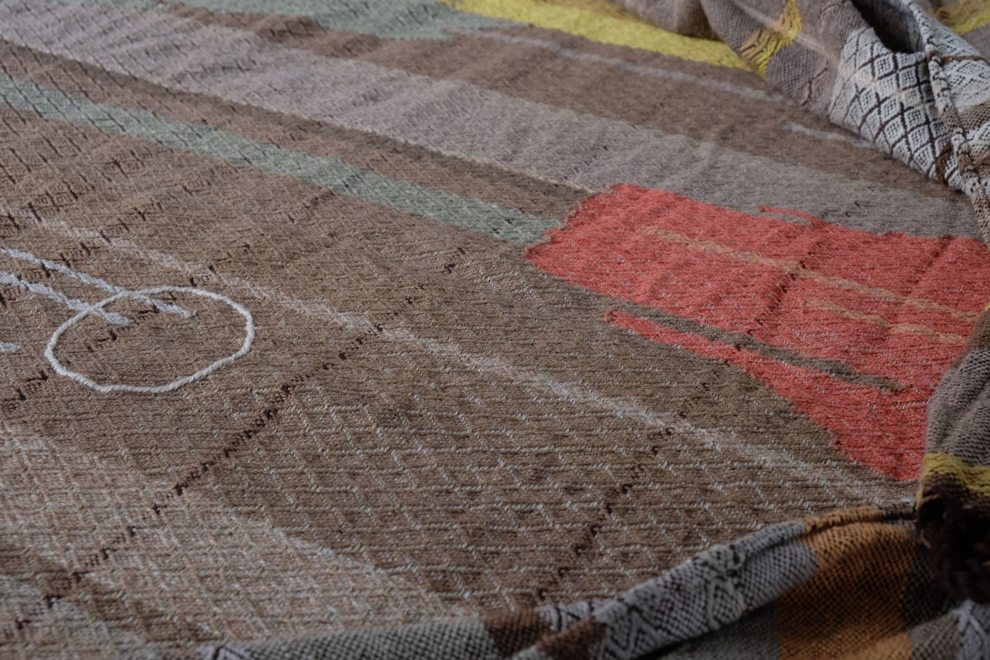 handwoven fabric with textured diamond pattern in soft earth tones of brown, salmon, green peach and yellow