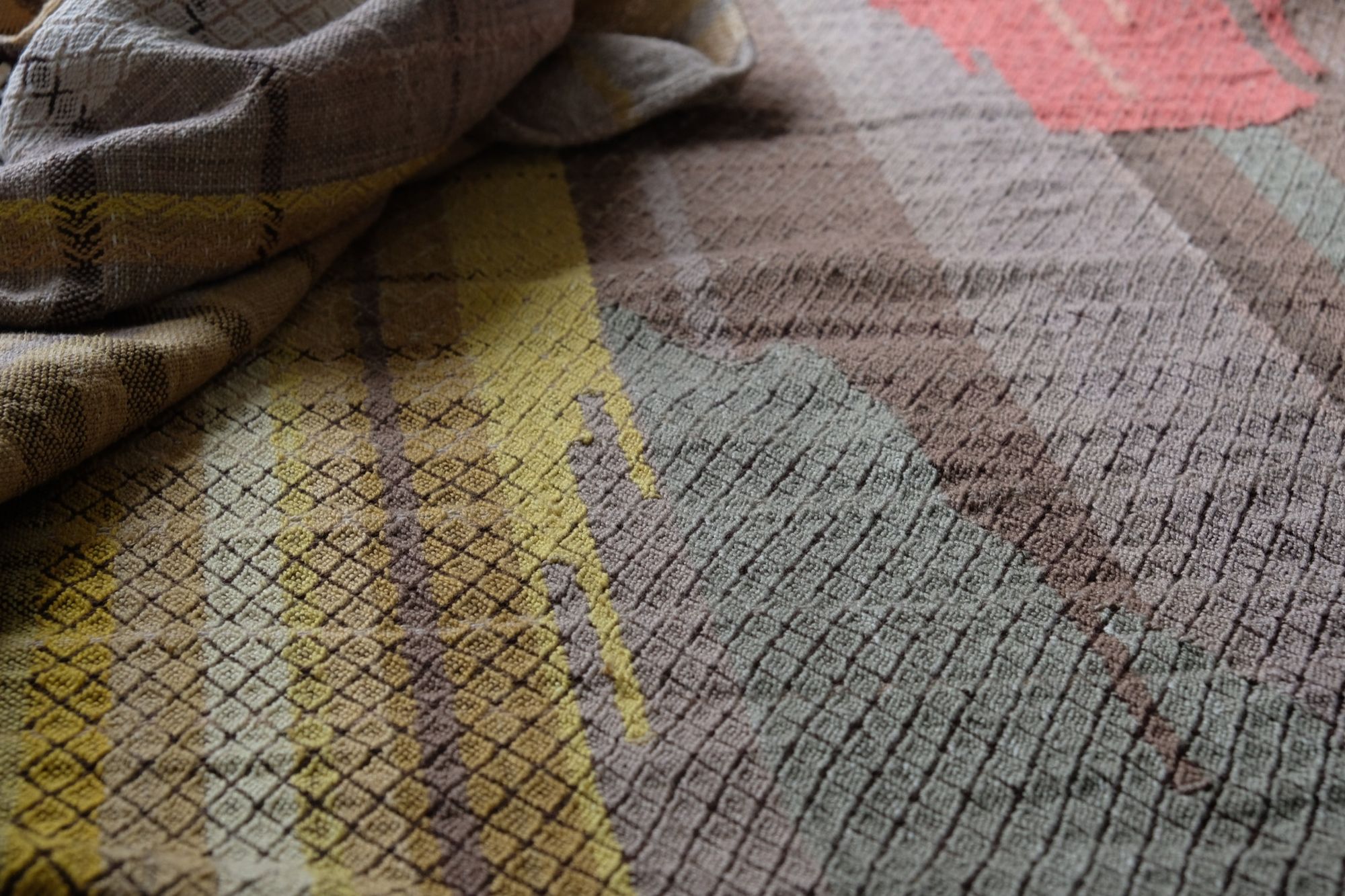 handwoven fabric with textured diamond pattern in soft earth tones of brown, salmon, green peach and yellow