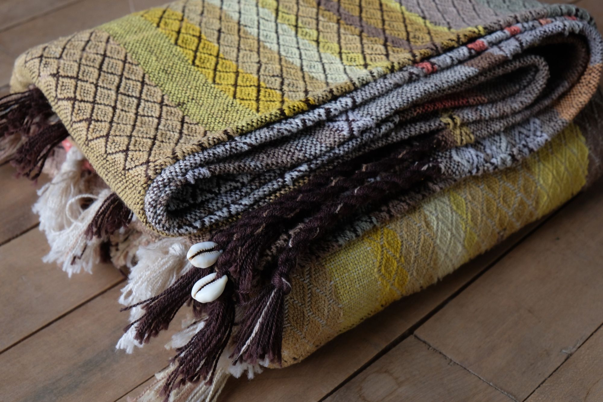 handwoven fabric with textured diamond pattern in soft earth tones of brown, salmon, green peach and yellow