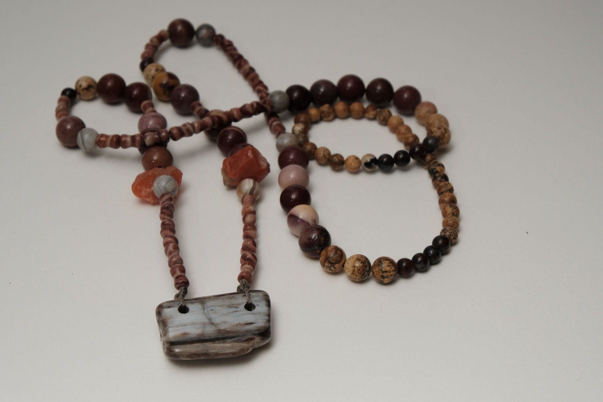 multicolored rough stone and petrified wood necklace laying on a white backdrop