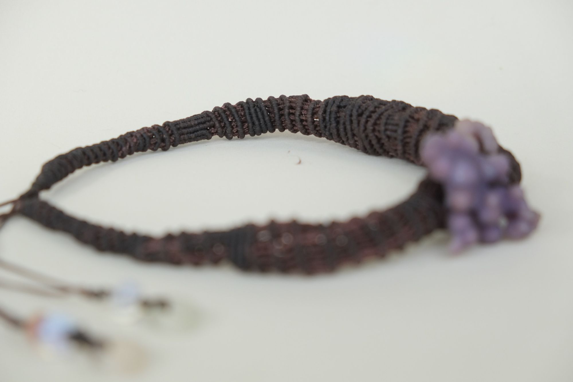 knot work necklace made with dark purple thread and purple grape chalcedony on a white backdrop