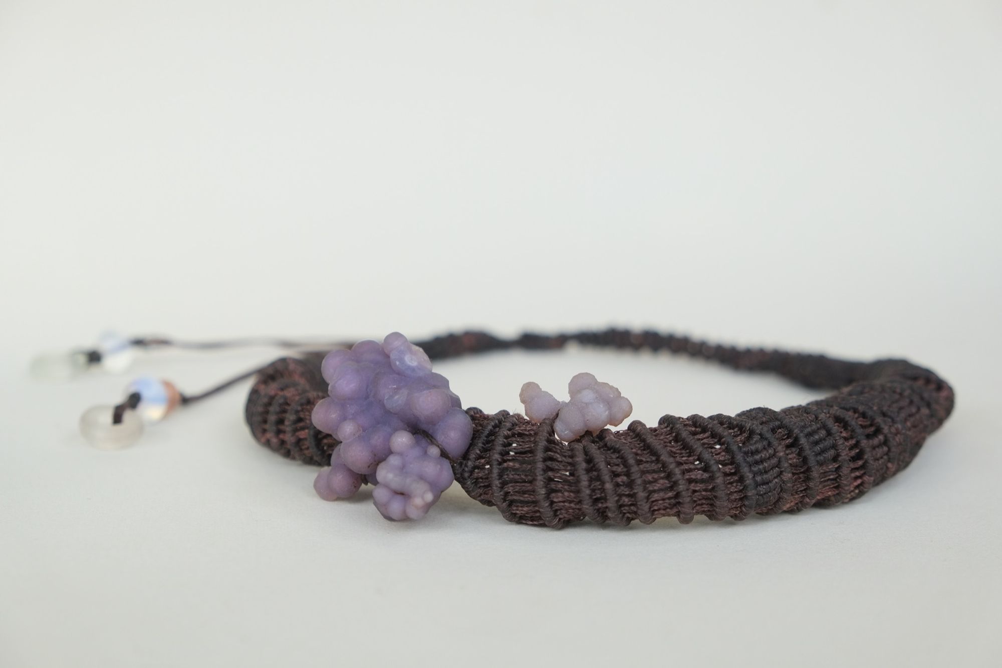 knot work necklace made with dark purple thread and purple grape chalcedony on a white backdrop