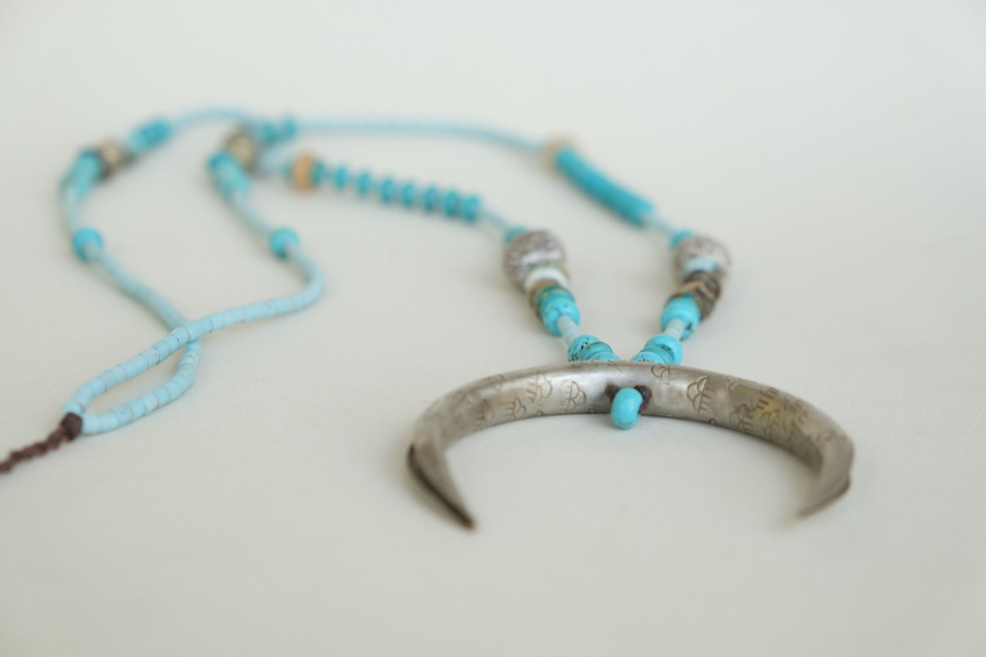 turquoise and blue stone necklace with a silver moon laying on a white backdrop