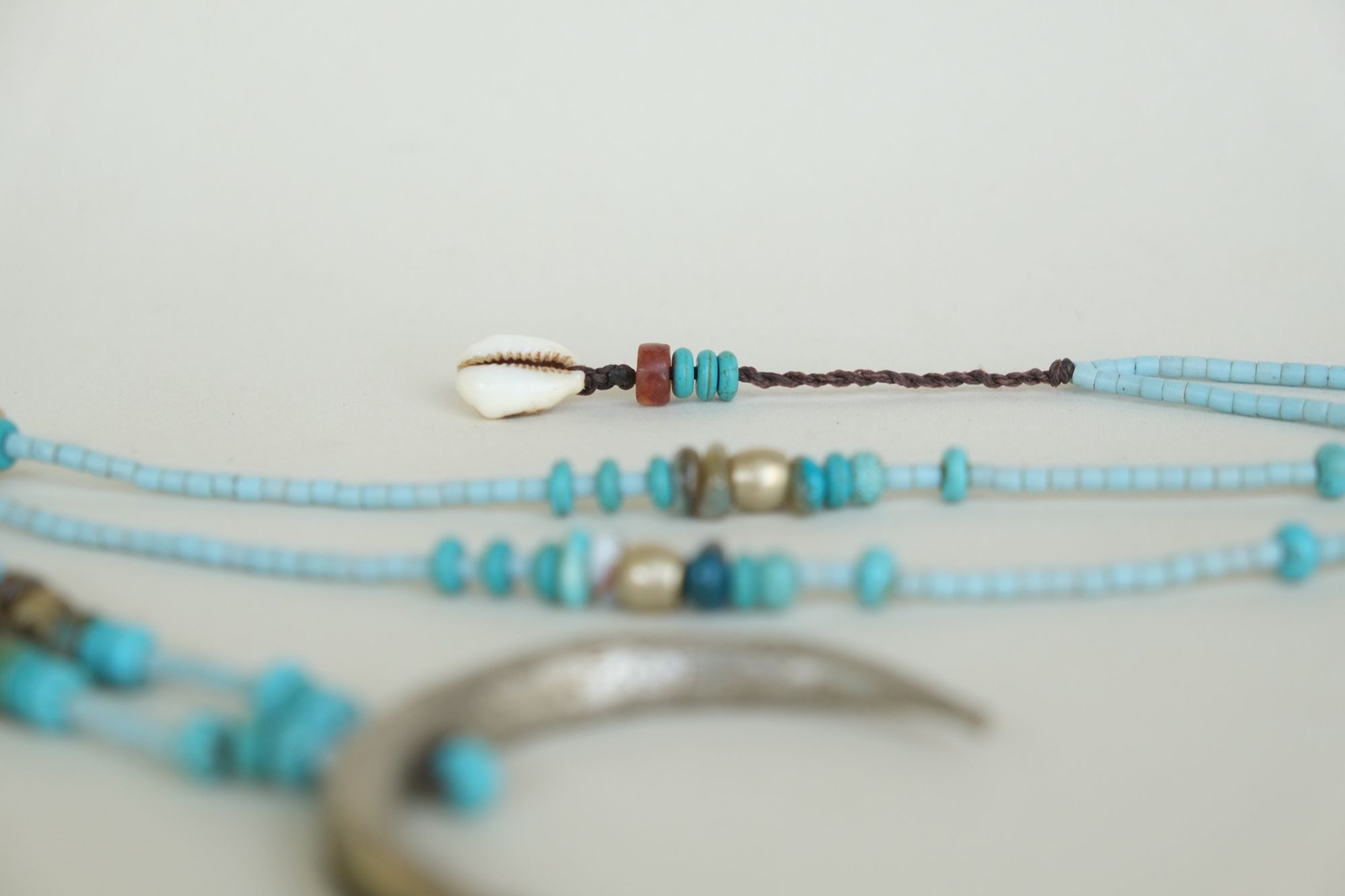 turquoise and blue stone necklace with a silver moon laying on a white backdrop