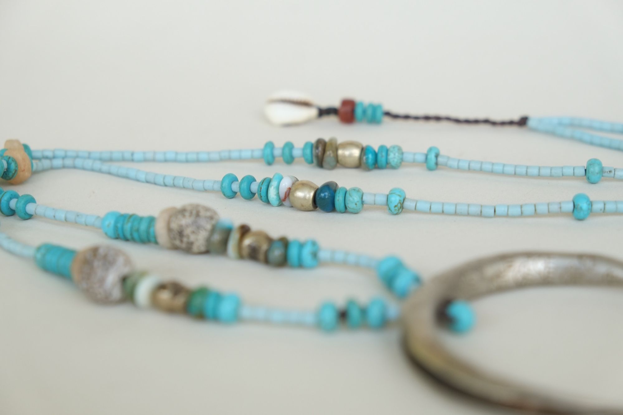 turquoise and blue stone necklace with a silver moon laying on a white backdrop
