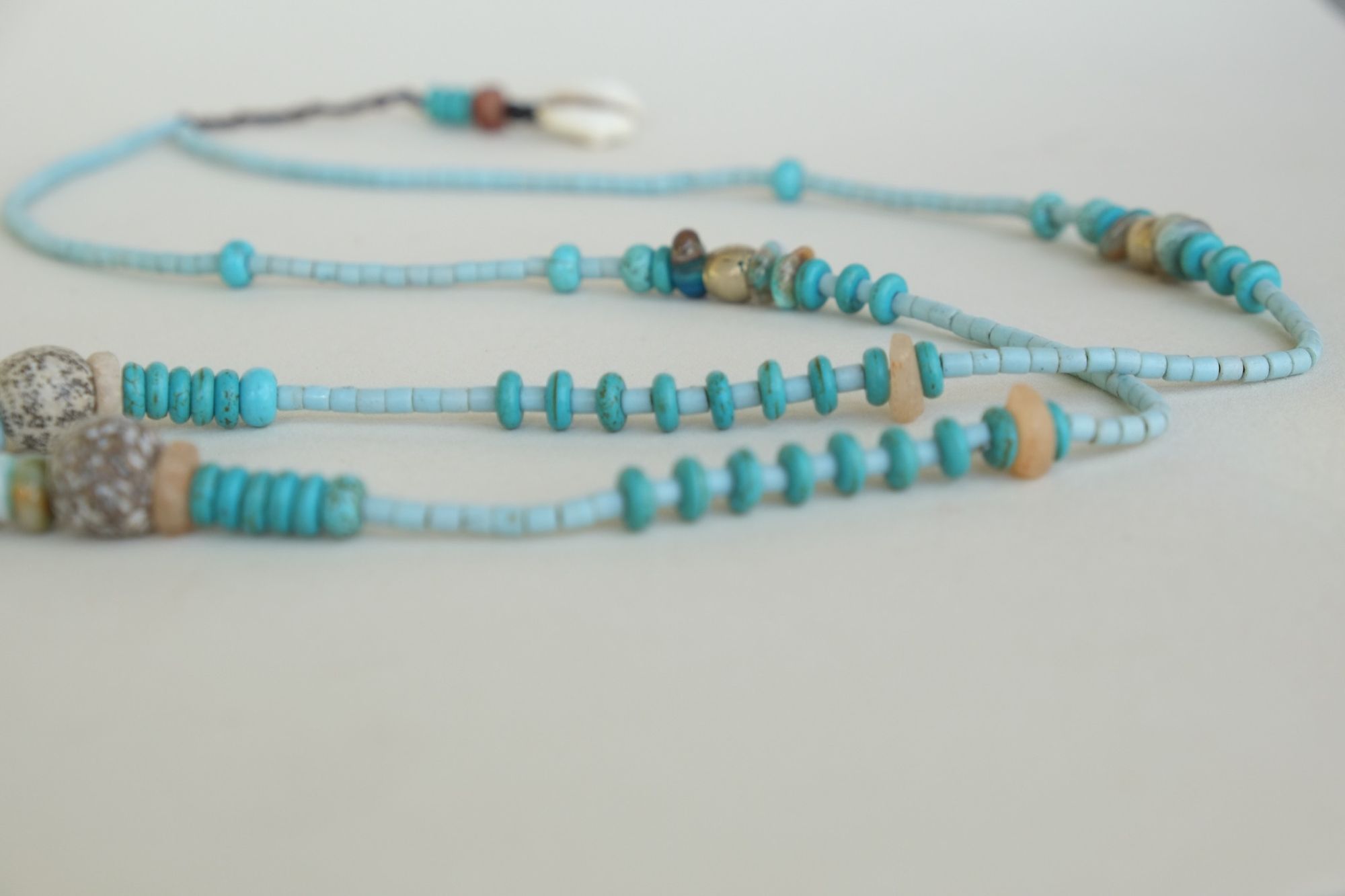 turquoise and blue stone necklace with a silver moon laying on a white backdrop