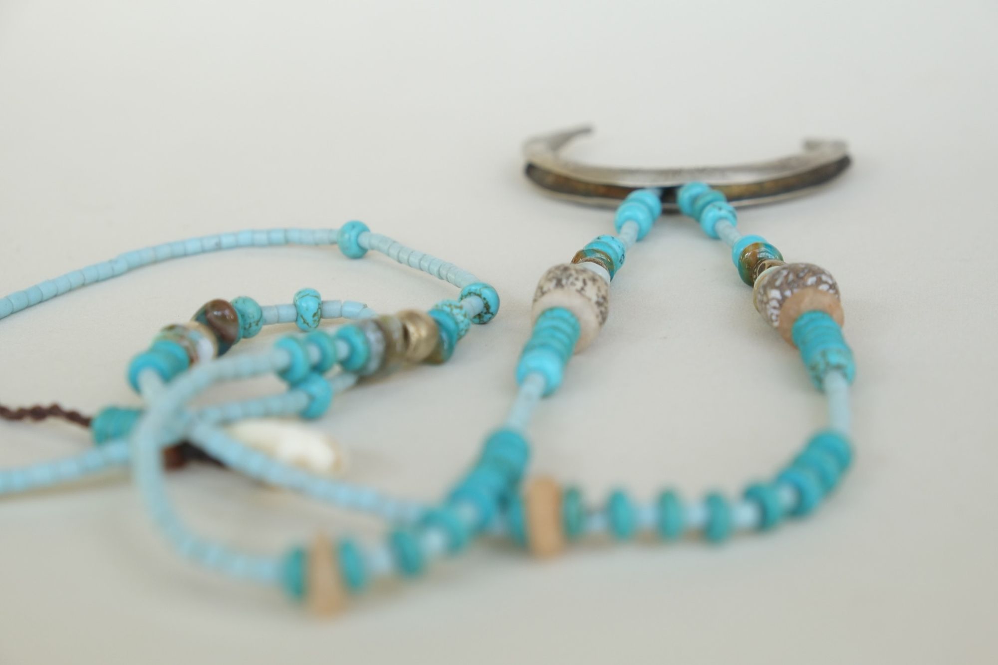 turquoise and blue stone necklace with a silver moon laying on a white backdrop