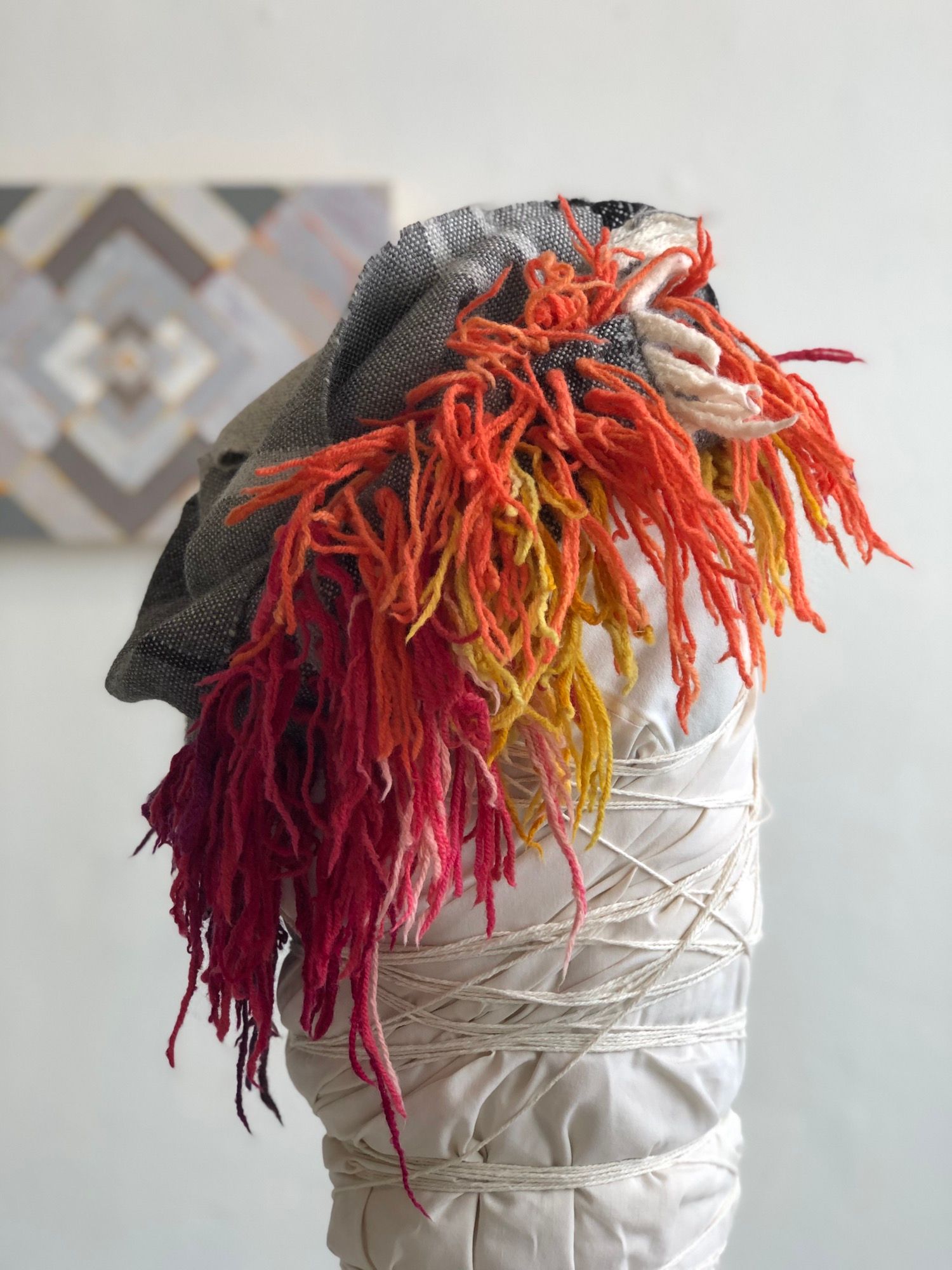 rainbow fringe, grey, black and white handwoven cowl scarf with fringe on a white mannequin in a white walled gallery