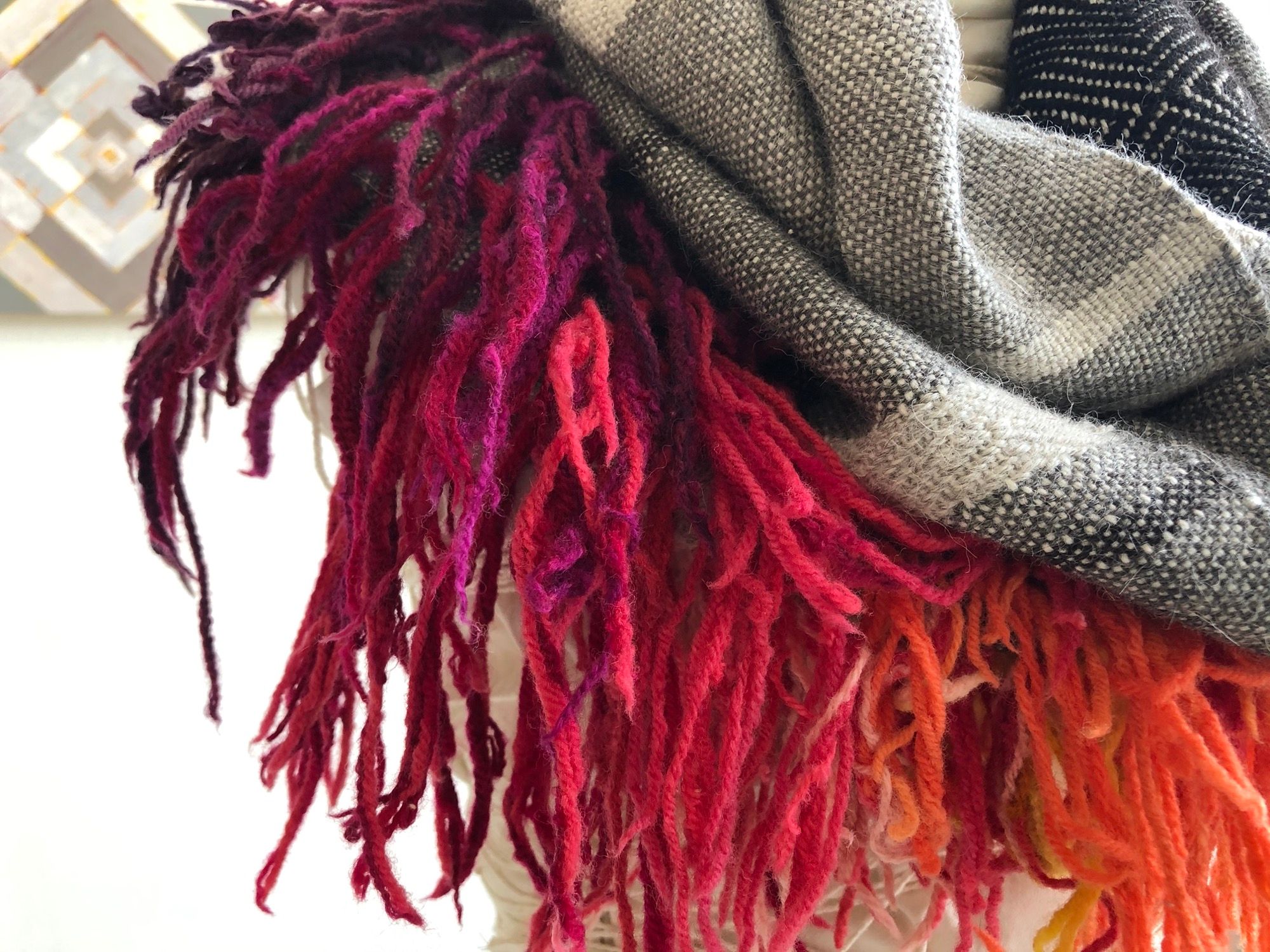 rainbow fringe, grey, black and white handwoven cowl scarf with fringe on a white mannequin in a white walled gallery