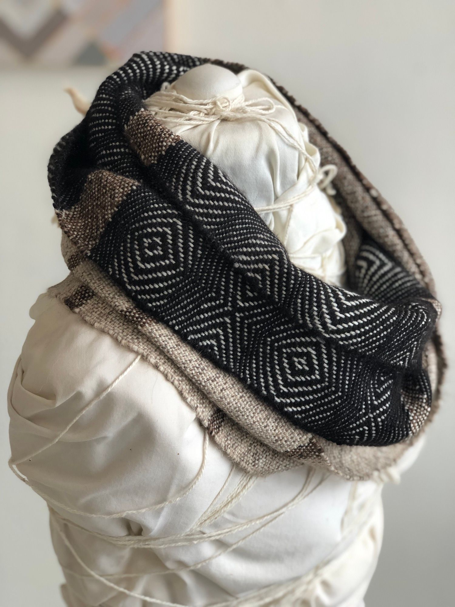 brown, grey, black and white handwoven cowl scarf with fringe on a white mannequin in a white walled gallery