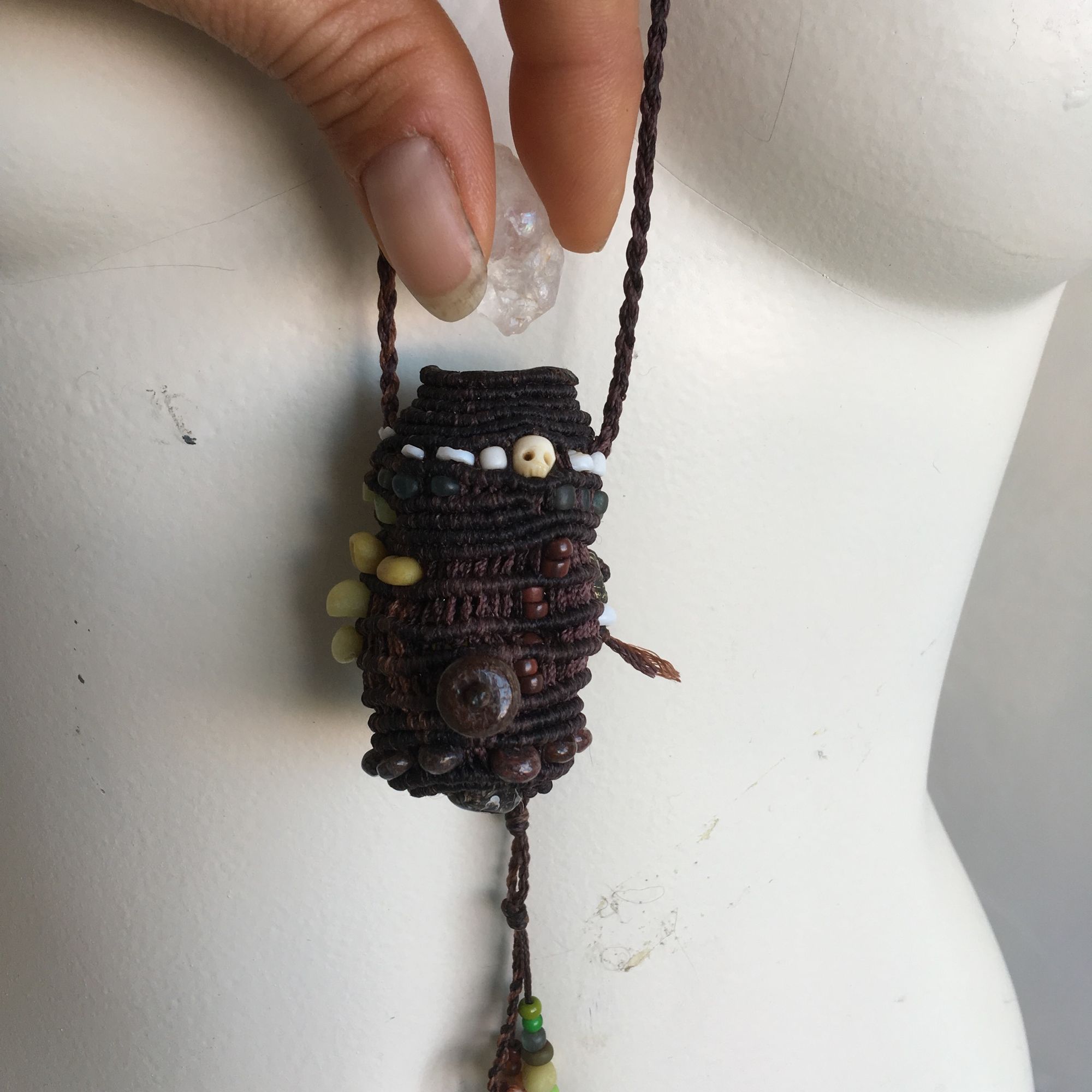 small knotted and beaded basket on a white mannequin in a white room