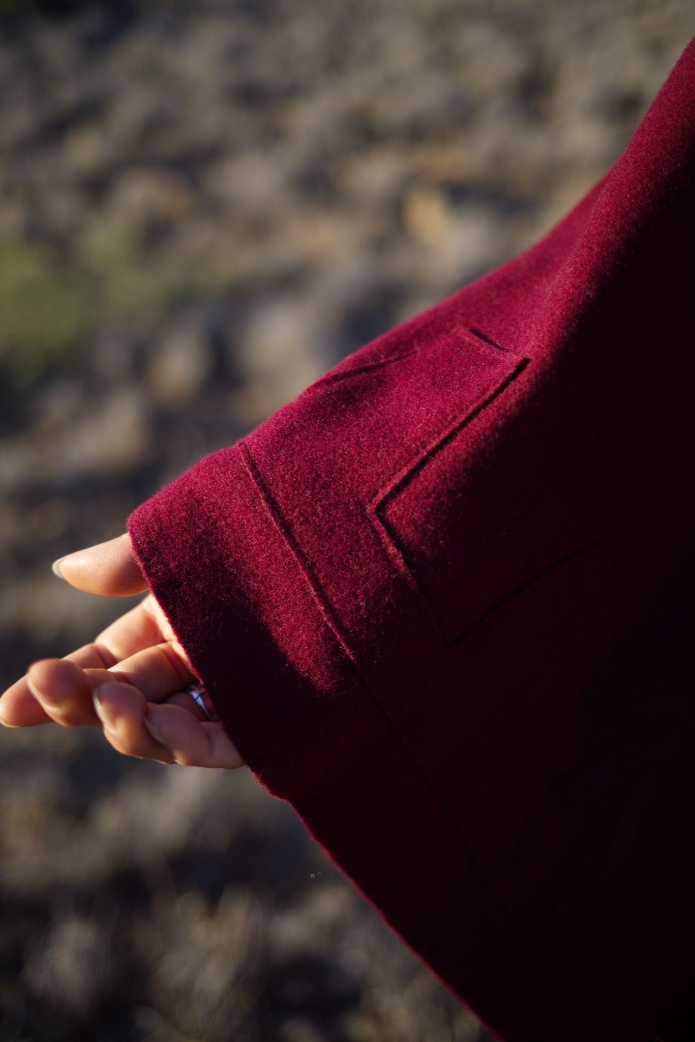 woman wearing a red, brown and rainbow cloak in the desert on a blue sky day