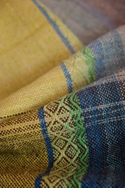 Handwoven fabric with diamond pattern in browns and all the colors of the rainbow, on a wooden floor