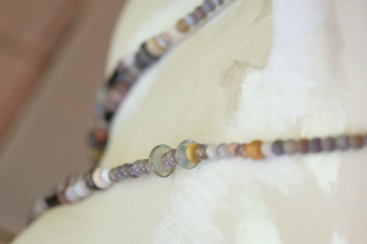 A white female form mannequin wears a two strand necklace made from pale purple amethyst crystal and earth tone stones