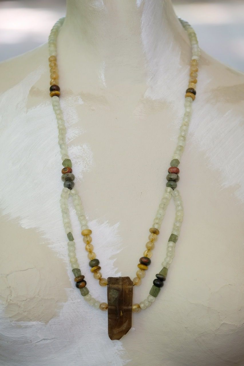 A white mannequin wears a Dark citrine and green, yellow and gold stone necklace 