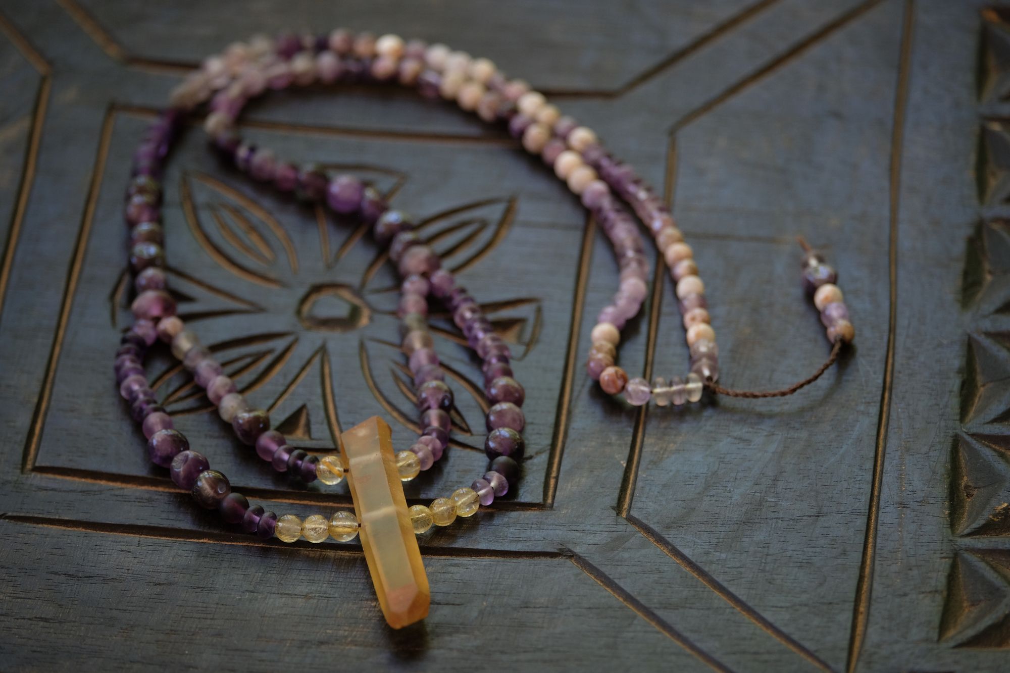  a purple and golden yellow stone necklace on a black wood surface 