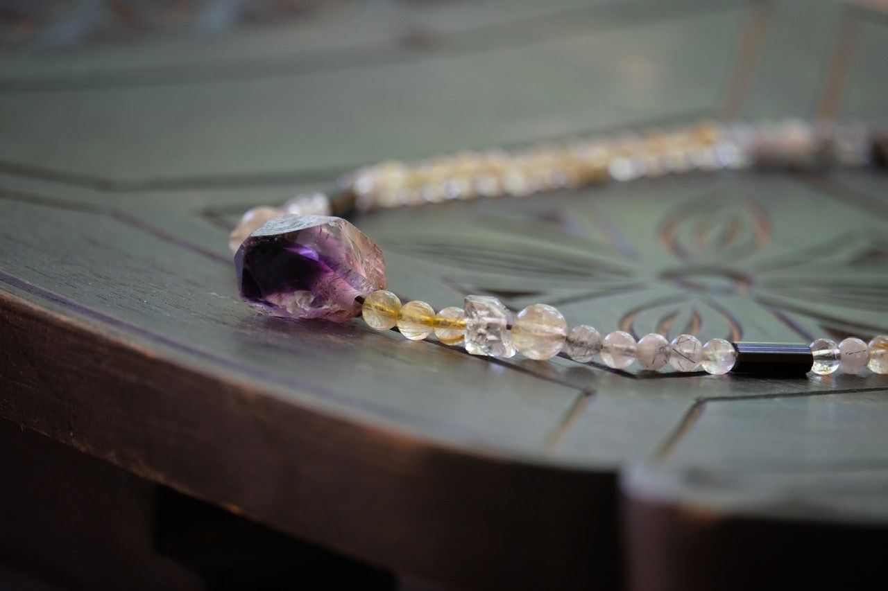 Deep purple amethyst and Quartz stones necklace on a black wood surface 