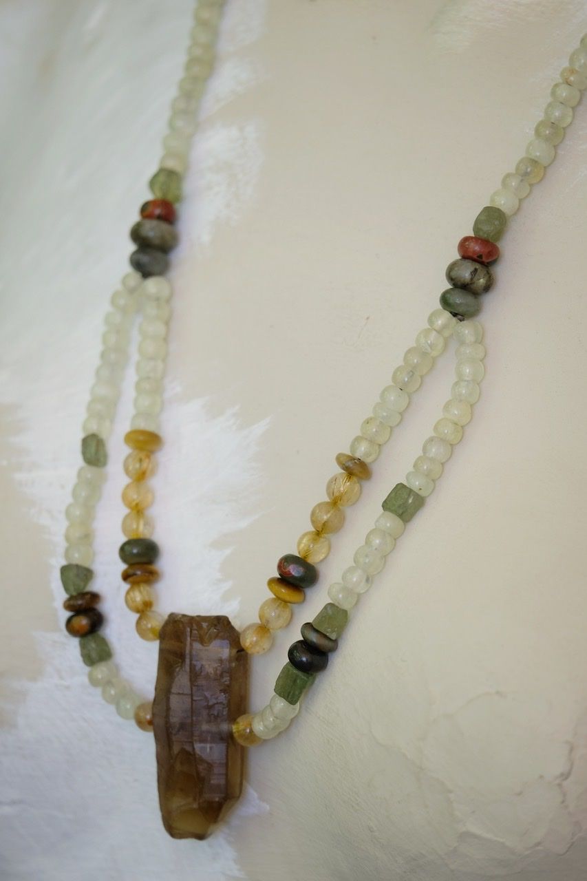 A white mannequin wears a Dark citrine and green, yellow and gold stone necklace 