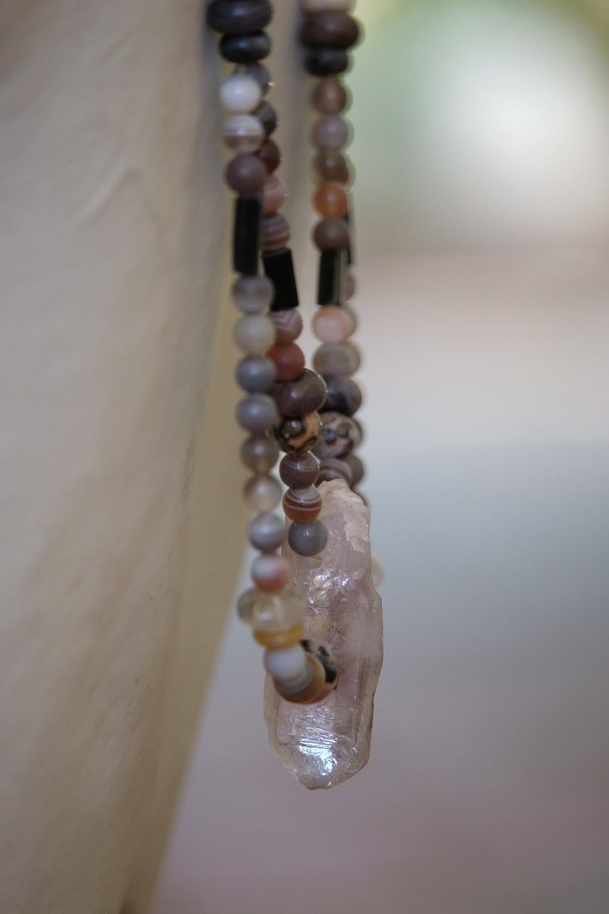 A white female form mannequin wears a two strand necklace made from pale purple amethyst crystal and earth tone stones