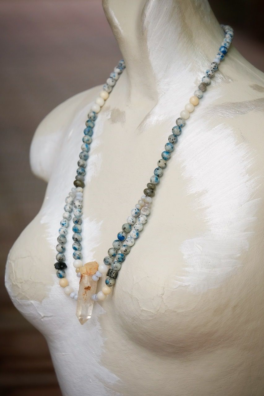 Blue, white and black stone and crystal necklace on a white mannequin 