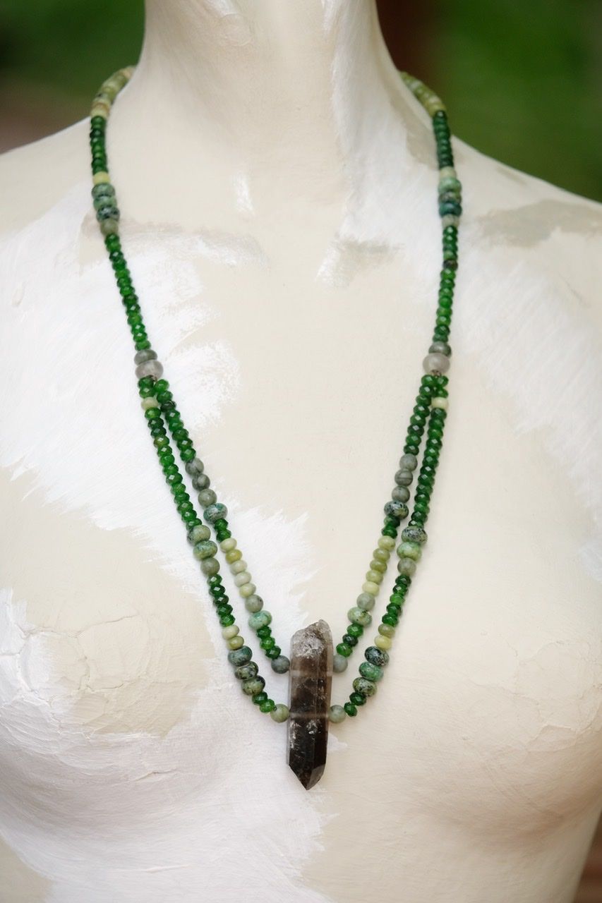Green and black stone and crystal necklace on a white mannequin 