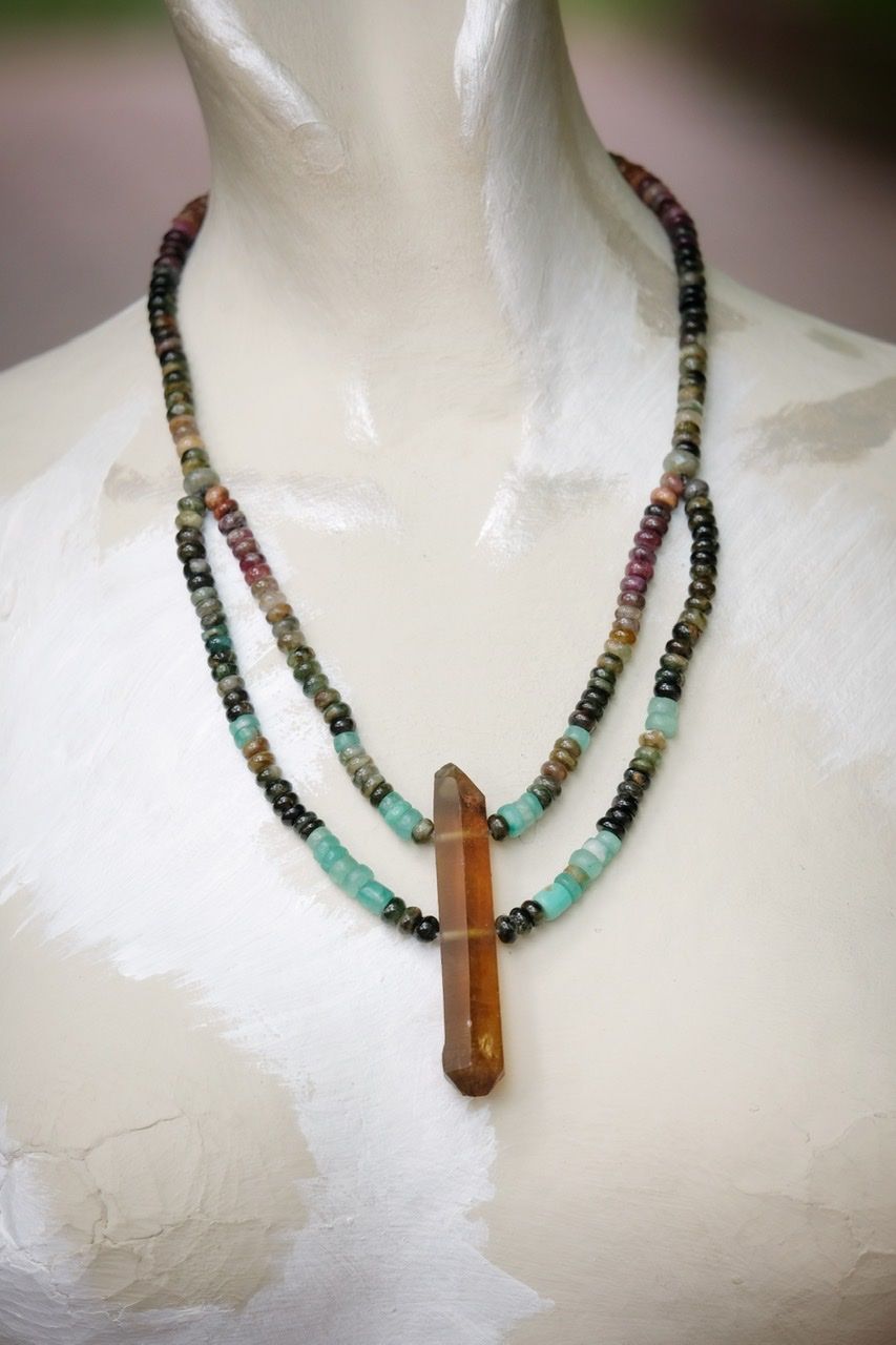 Deep pink, green, blue, emerald green and rich yellow stone and crystal necklace on a white mannequin 