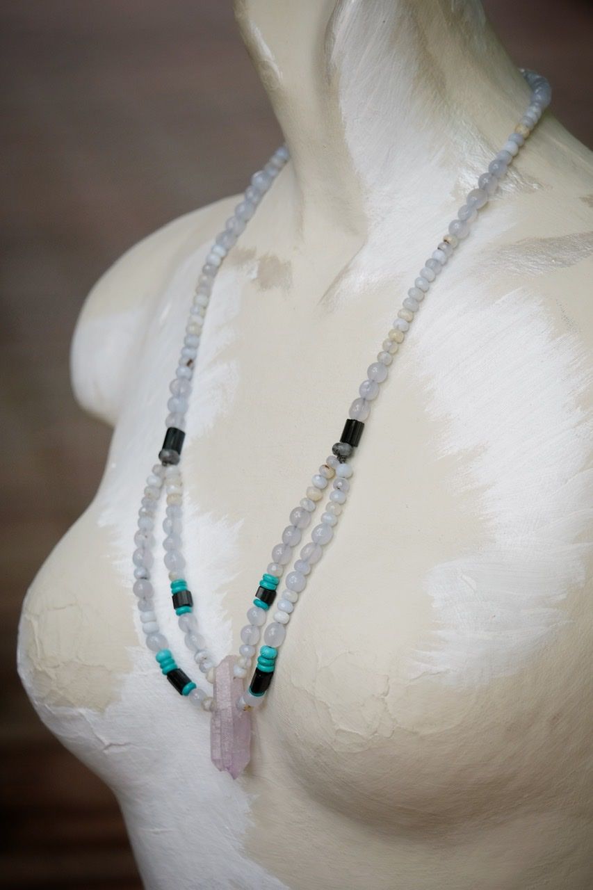 Pale blue, pale purple, black and turquoise stone and crystal necklace on a white mannequin 