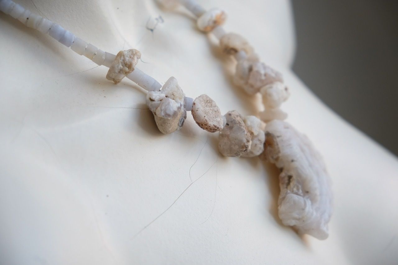 A white colored female form mannequin wears a necklace of white and blue botryoidal chalcedony