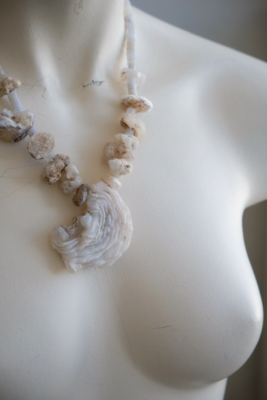 A white colored female form mannequin wears a necklace of white and blue botryoidal chalcedony