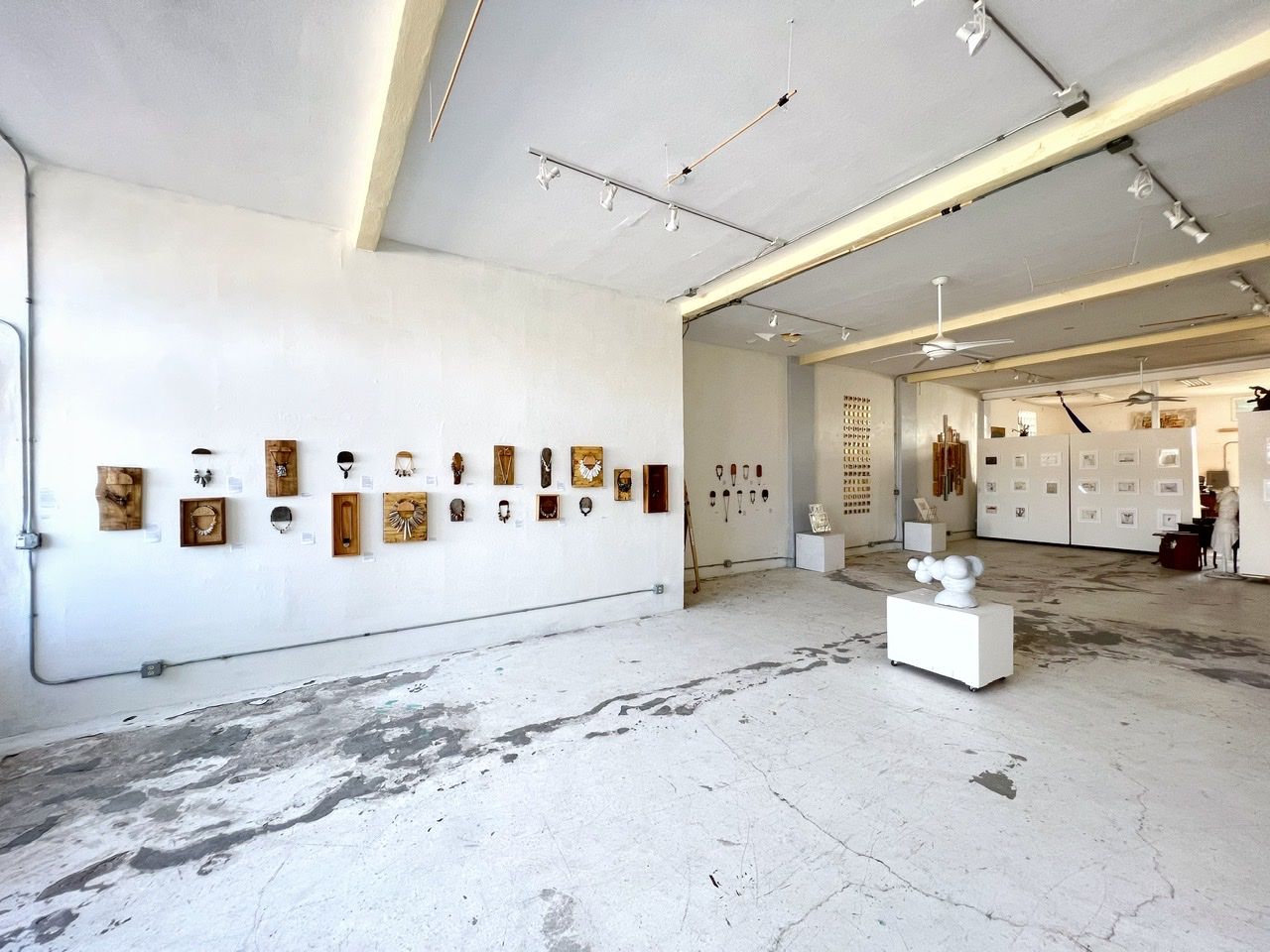 the interior view of a gallery with a marble sculpture of a molecule on the floor and art on the white walls