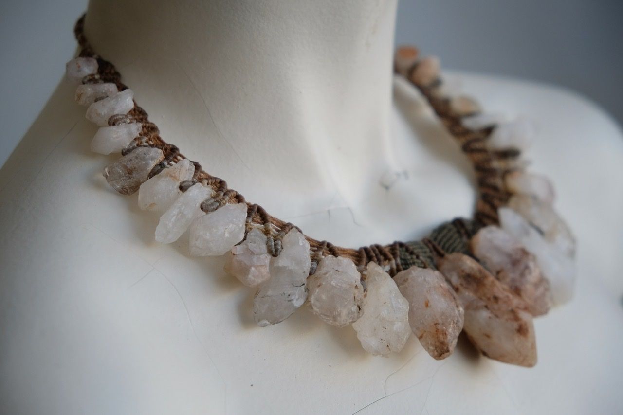 A white colored female form mannequin wears a sculptural necklace of rough quartz points and knotwork