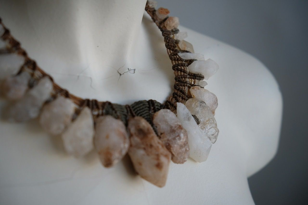 A white colored female form mannequin wears a sculptural necklace of rough quartz points and knotwork