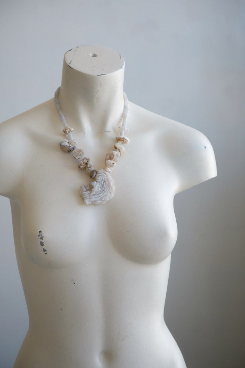 A white colored female form mannequin wears a necklace of white and blue botryoidal chalcedony