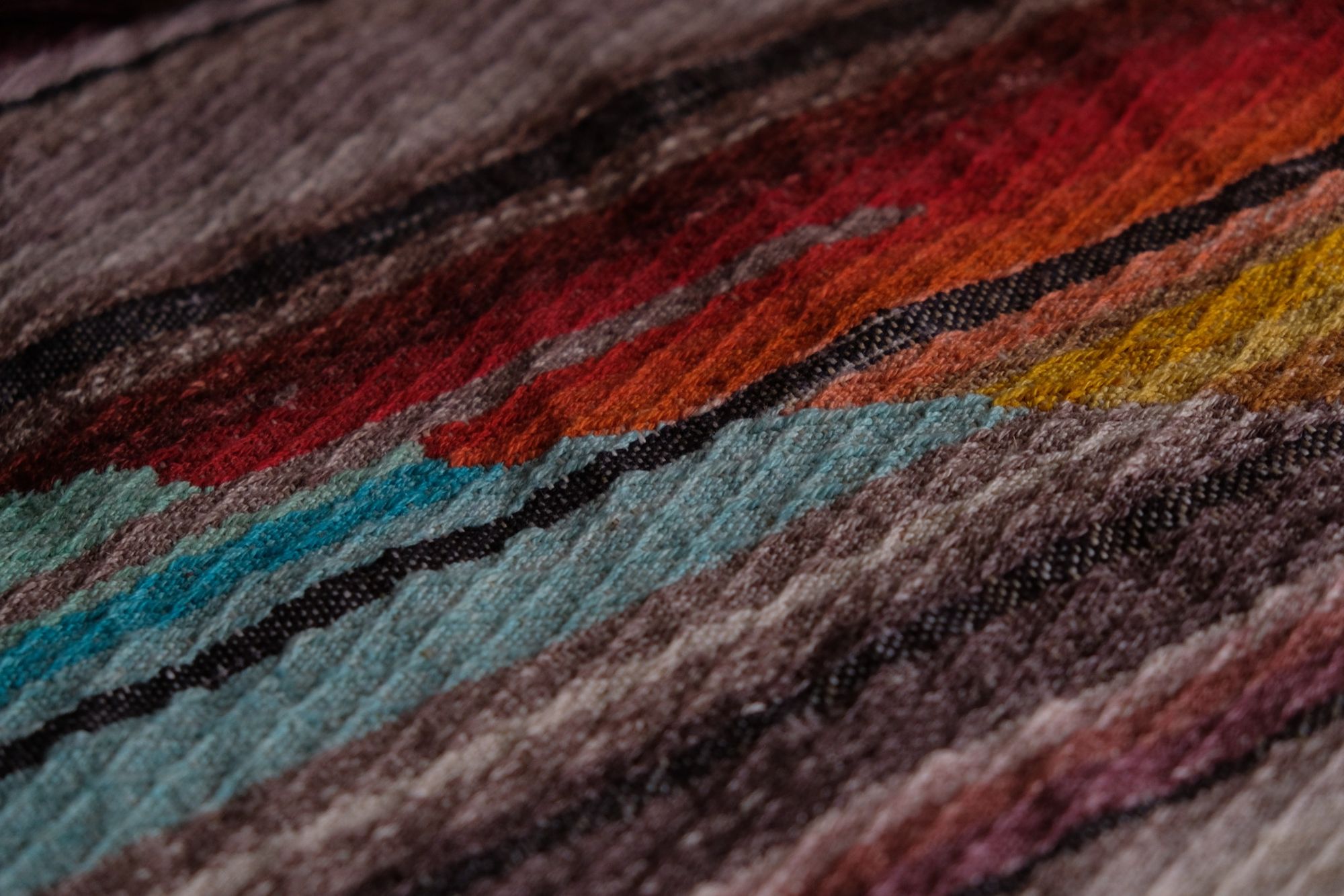 details of geometric shaped, natural and rainbow colored handwoven, diamond pattern fabric on a wooden floor