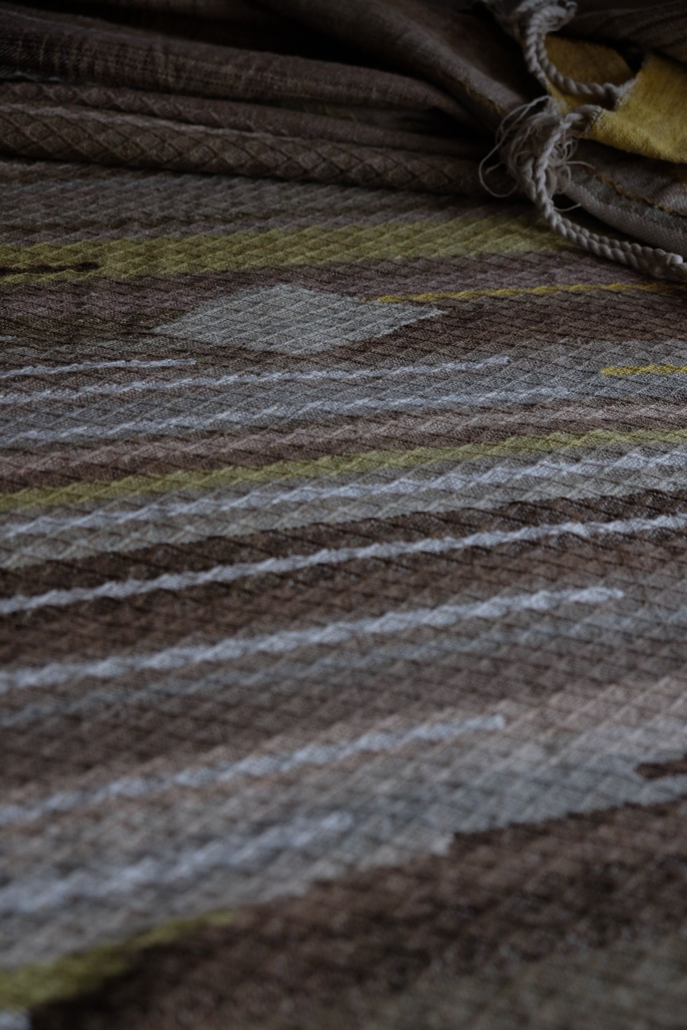 detail of handwoven diamond pattern and geometric details in browns, tan, yellows, whites and pinks