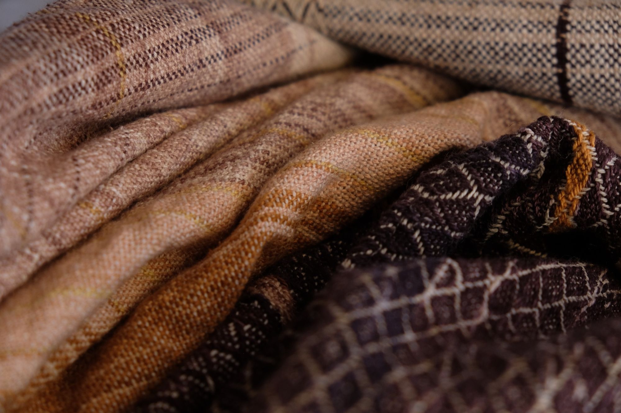handwoven fabric with plain and diamond pattern in grey, brick reds, black, blue, golden yellows, white and pink