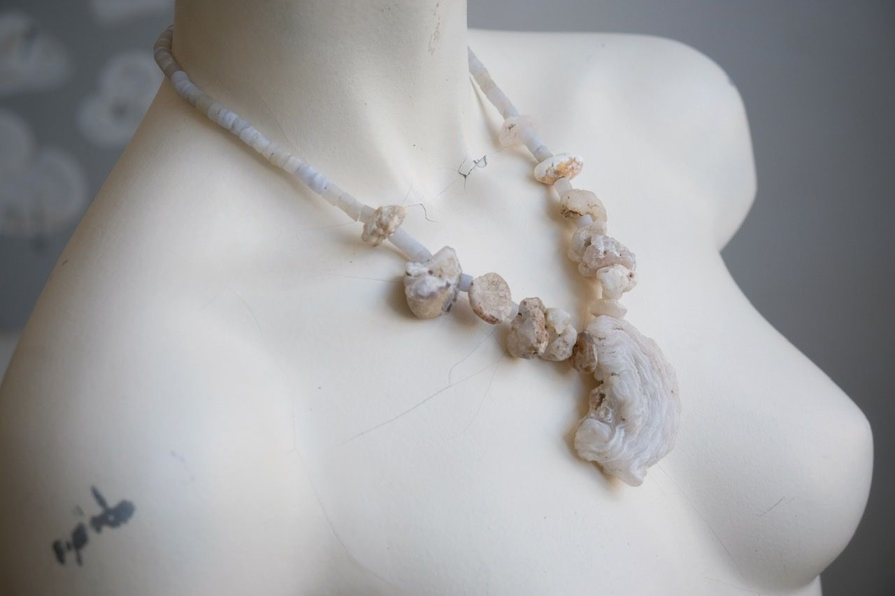 A white colored female form mannequin wears a necklace of white and blue botryoidal chalcedony